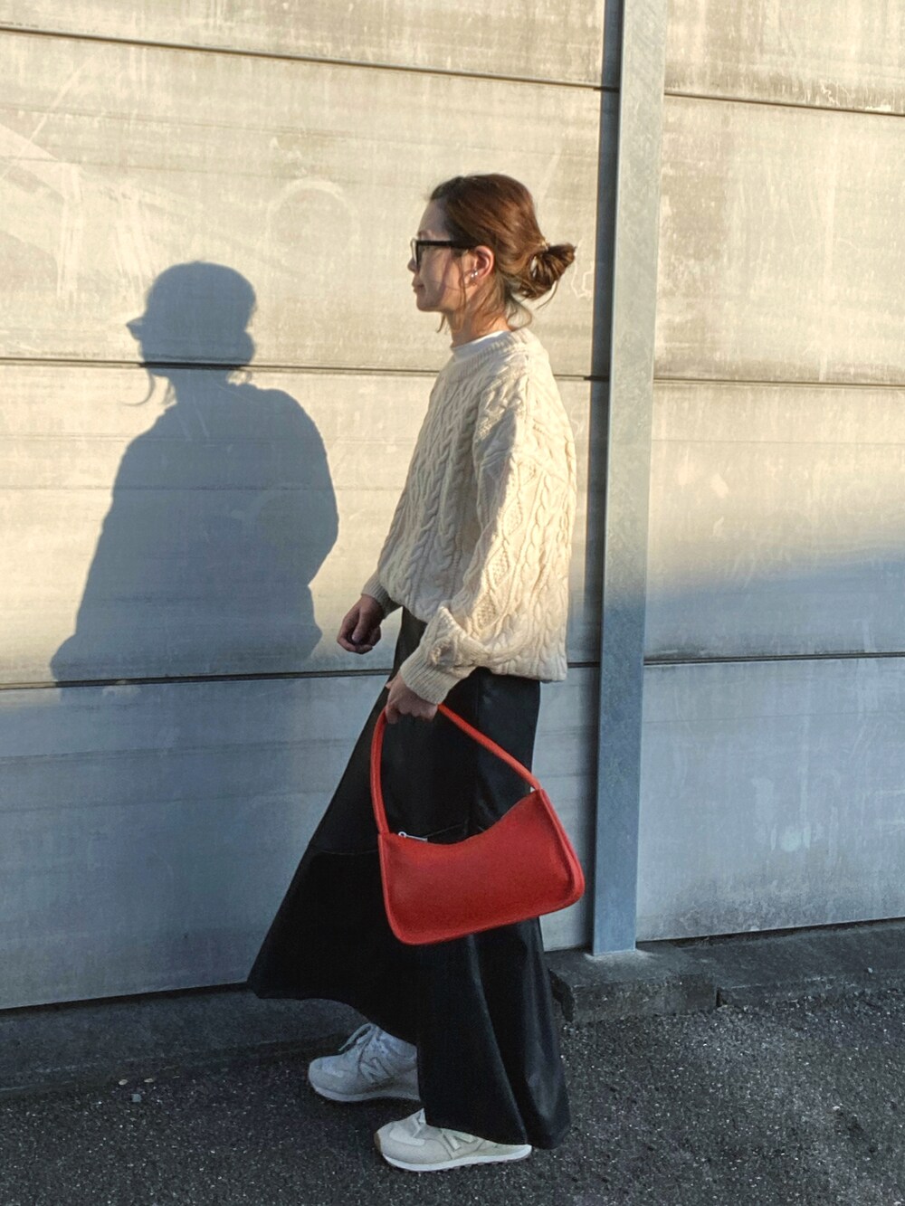 ホワイト系のニット/セーター、ブラック系のスカート、オレンジ系のショルダーバッグを着用したレディースの秋コーディネートの3枚目の写真