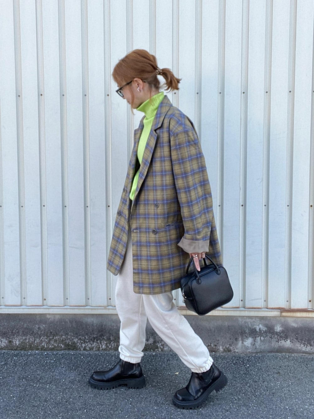 イエロー系のテーラードジャケット、ブラック系のボストンバッグ、ブラック系のブーツを着用したレディースの冬コーディネートの2枚目の写真