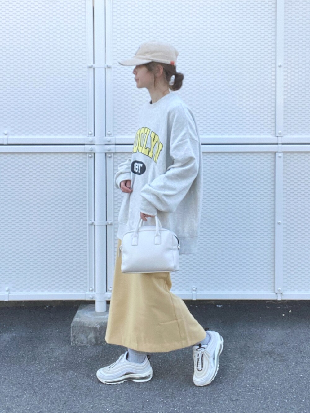 ベージュ系のスウェット、イエロー系のスカート、ホワイト系のボストンバッグを着用したレディースの冬コーディネートの3枚目の写真