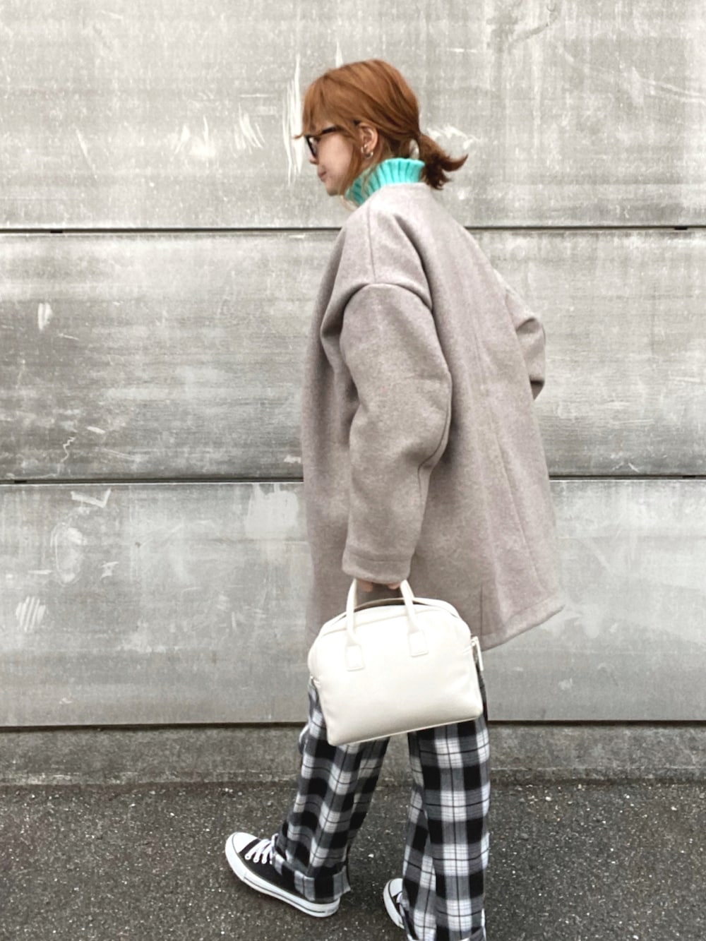 ベージュ系のノーカラーコート、ブルー系のニット/セーター、ホワイト系のスラックスを着用したレディースの冬コーディネートの3枚目の写真