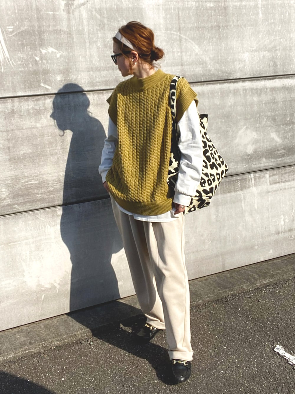 イエロー系のベスト、ホワイト系のTシャツ/カットソー、ブラック系のトートバッグを着用したレディースの春コーディネートの2枚目の写真