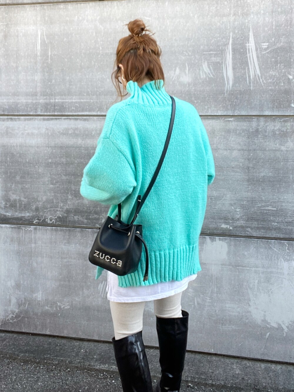 ブラック系のショルダーバッグ、ブルー系のニット/セーター、ブラック系のブーツを着用したレディースの冬コーディネートの3枚目の写真