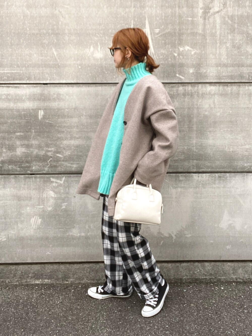 ベージュ系のノーカラーコート、ブルー系のニット/セーター、ホワイト系のスラックスを着用したレディースの冬コーディネートの2枚目の写真