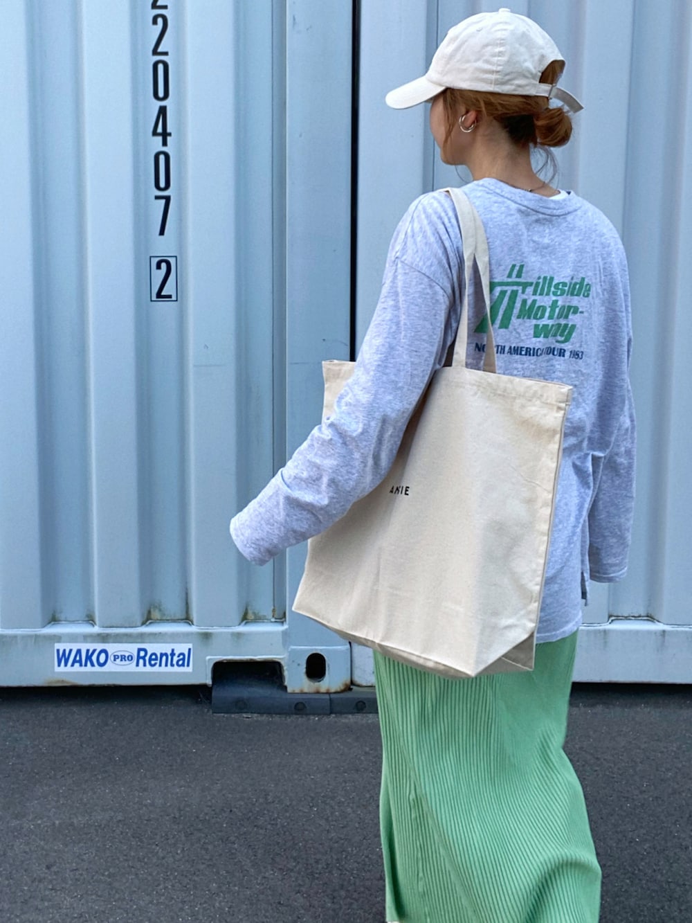 ホワイト系のエコバッグ/サブバッグ、グレー系のTシャツ/カットソー、グリーン系のスカートを着用したレディースの春コーディネートの3枚目の写真