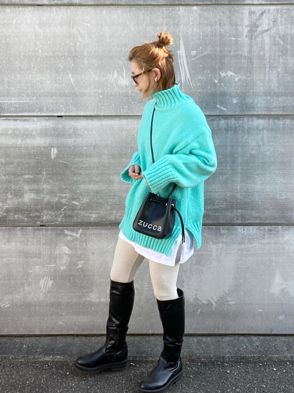 ブラック系のショルダーバッグ、ブルー系のニット/セーター、ブラック系のブーツを着用したレディースの冬コーディネートの2枚目の写真