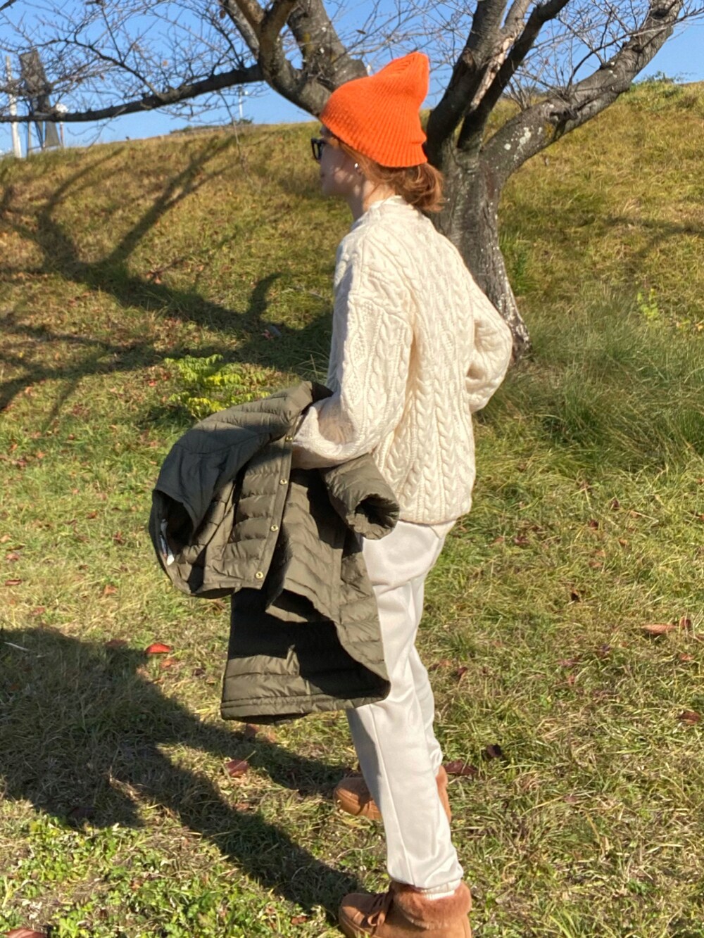 グリーン系のダウンジャケット/コート、ホワイト系のニット/セーター、ブラウン系のトートバッグを着用したレディースの冬コーディネートの3枚目の写真