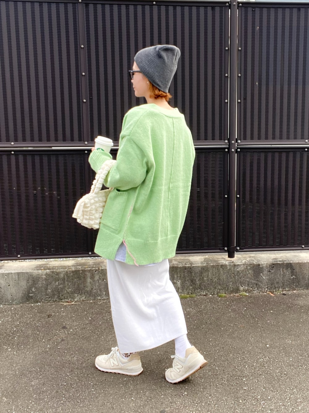 グリーン系のカーディガン/ボレロ、グレー系のTシャツ/カットソー、ホワイト系のスカートを着用したレディースの秋コーディネートの2枚目の写真