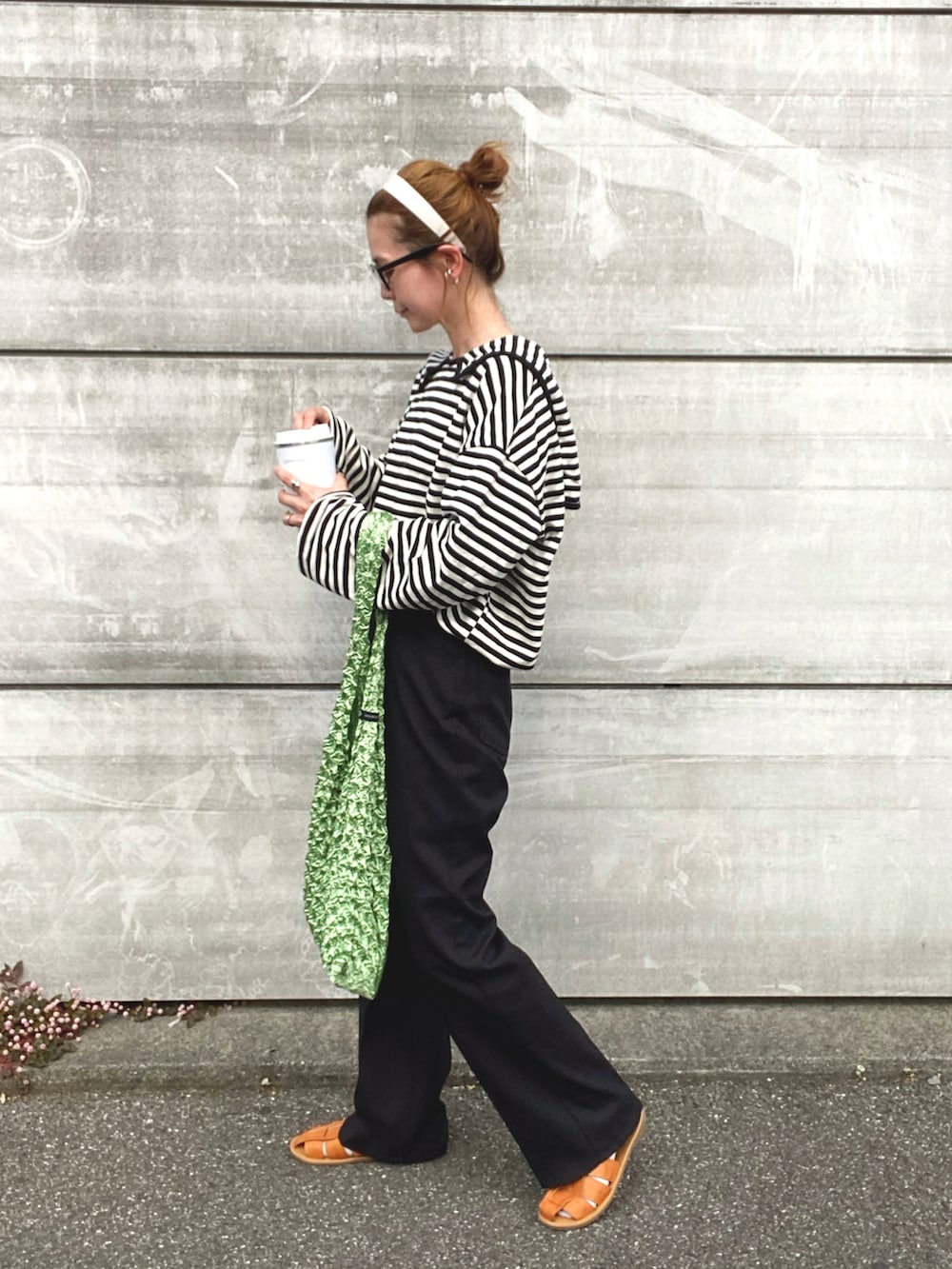 ブラック系のスラックス、ブラウン系のサンダル、ブルー系のトートバッグを着用したレディースの春コーディネートの3枚目の写真