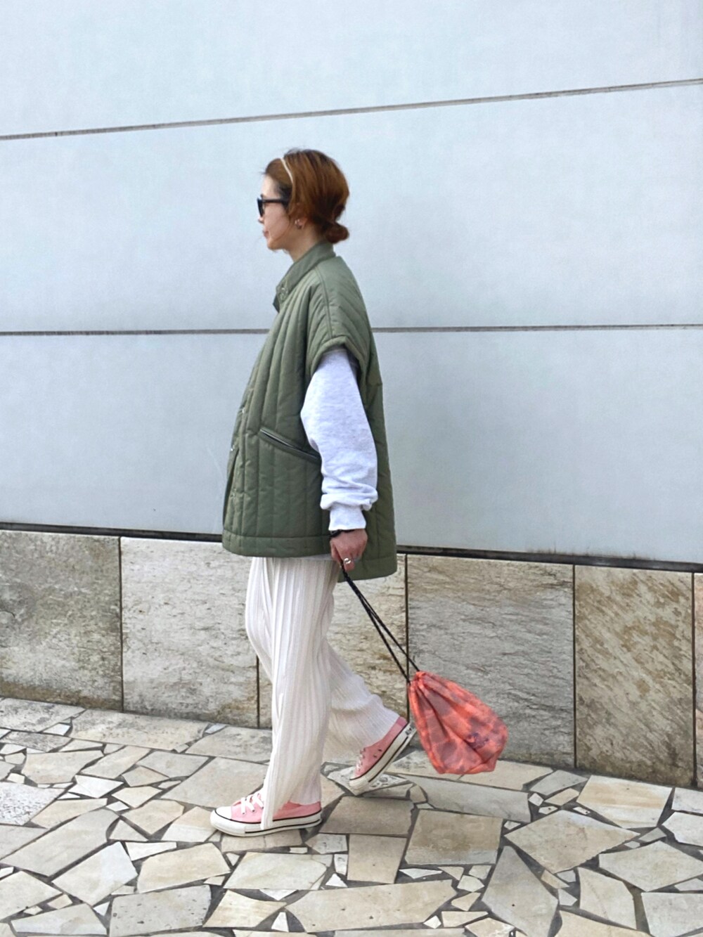 ホワイト系のその他パンツ、グリーン系のベスト、オレンジ系のショルダーバッグを着用したレディースの春コーディネートの3枚目の写真