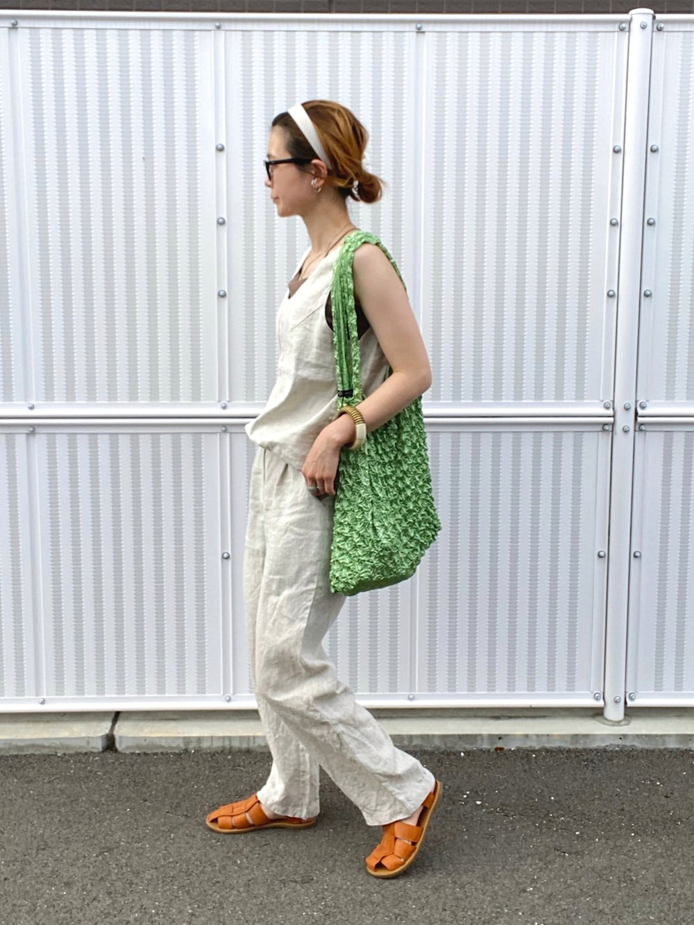 ベージュ系のタンクトップ、ブラウン系のキャミソール、ベージュ系のスラックスを着用したレディースの夏コーディネートの2枚目の写真