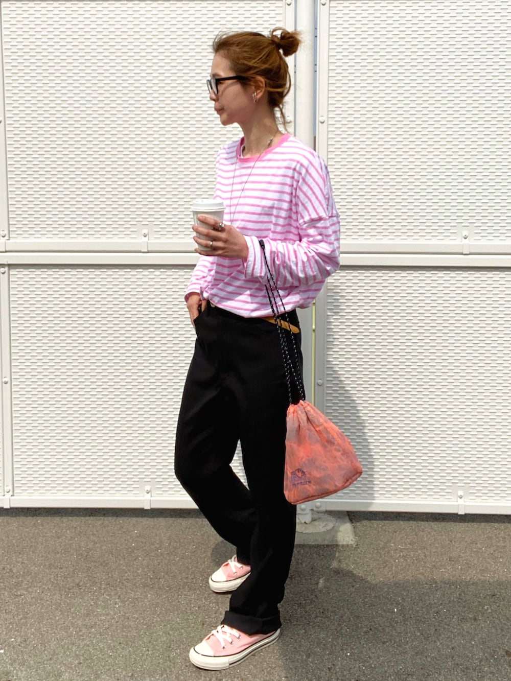 ブラック系のスラックス、ピンク系のスニーカー、オレンジ系のショルダーバッグを着用したレディースの春コーディネートの3枚目の写真