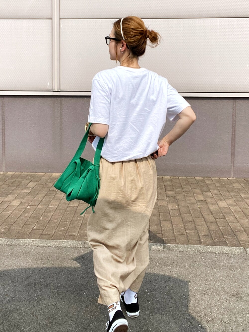 ベージュ系のスカート、ブラック系のスニーカー、グリーン系のトートバッグを着用したレディースの春コーディネートの3枚目の写真