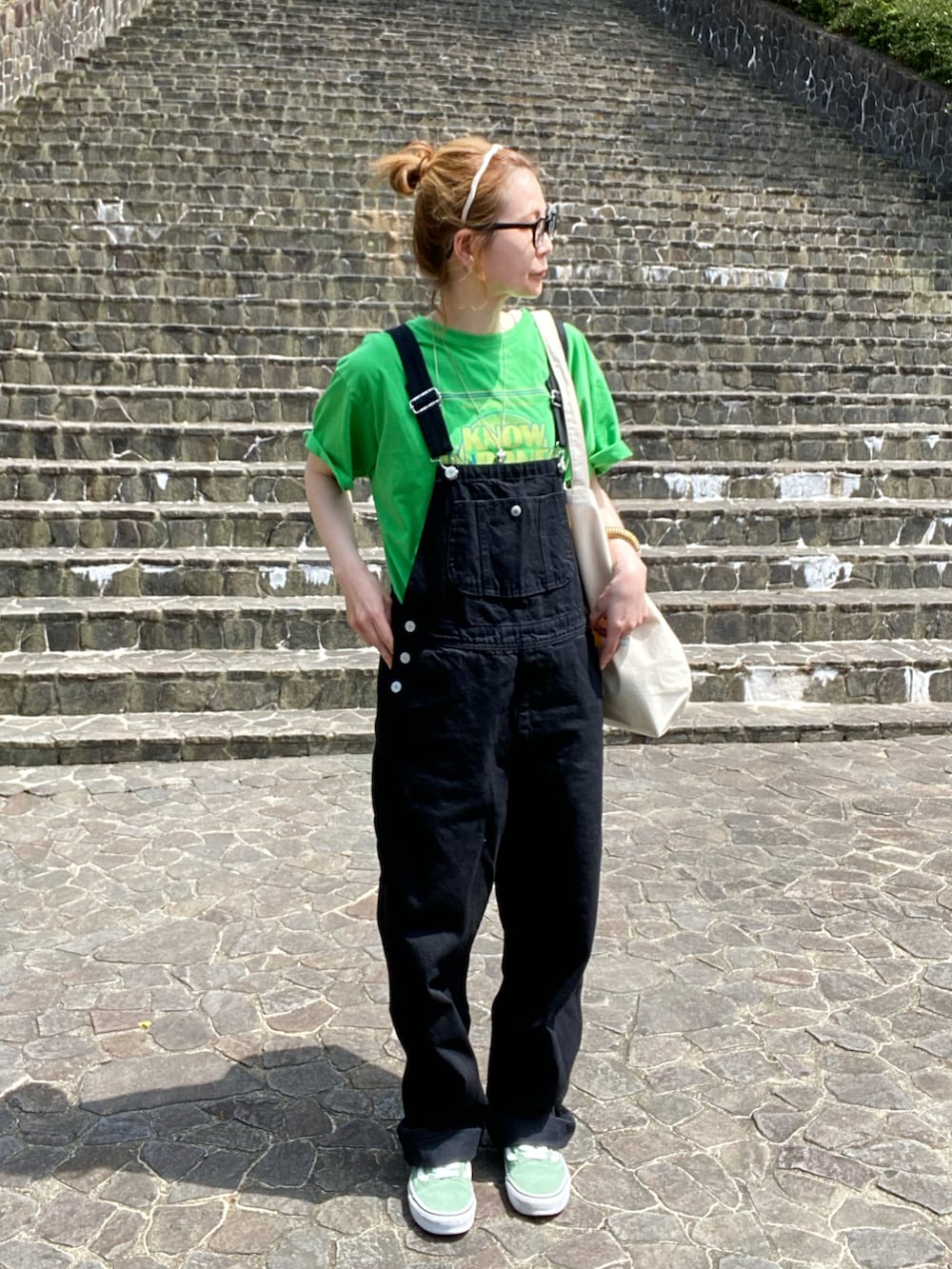 ブラック系のサロペット/オーバーオール、グリーン系のTシャツ/カットソー、グリーン系のスニーカーを着用したレディースの春コーディネートの4枚目の写真