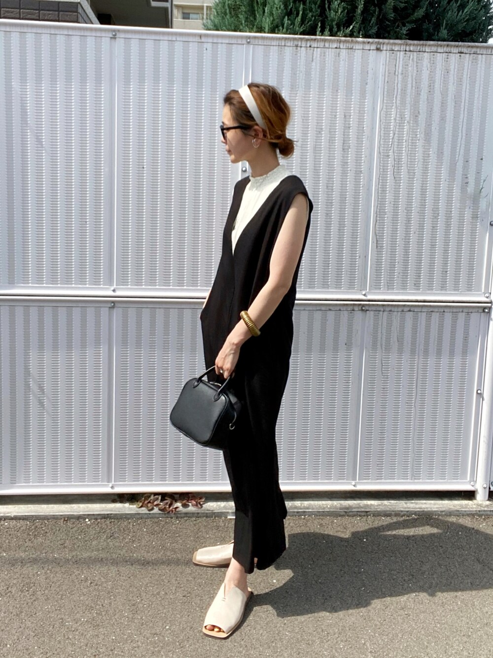 ブラック系のワンピース、ホワイト系のサンダル、ブラック系のボストンバッグを着用したレディースの夏コーディネートの2枚目の写真