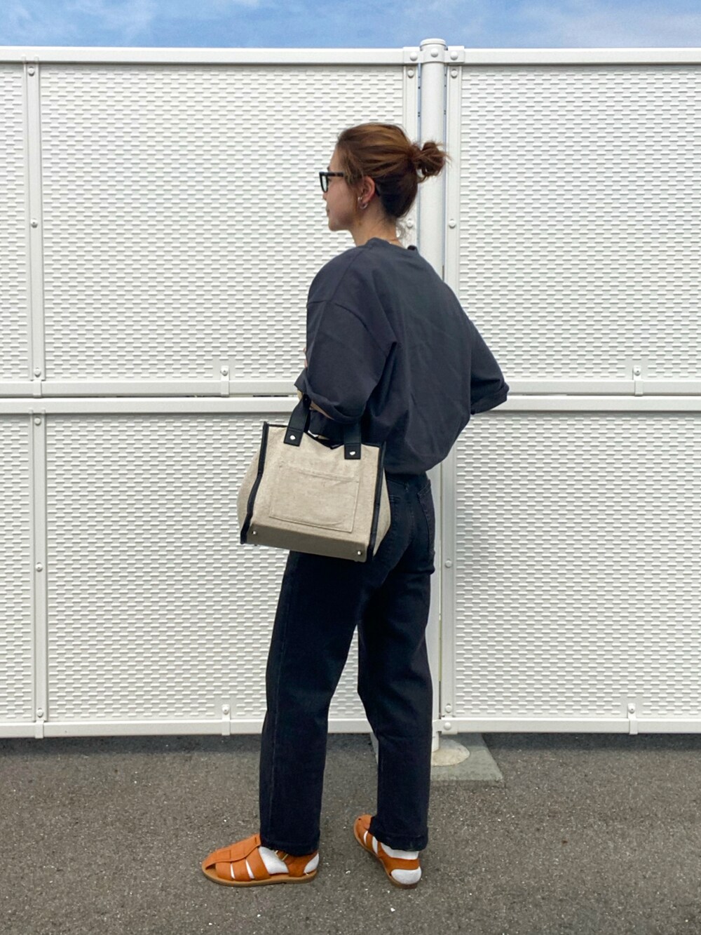 ブラウン系のサンダル、ブラック系のTシャツ/カットソー、ベージュ系のトートバッグを着用したレディースの春コーディネートの4枚目の写真