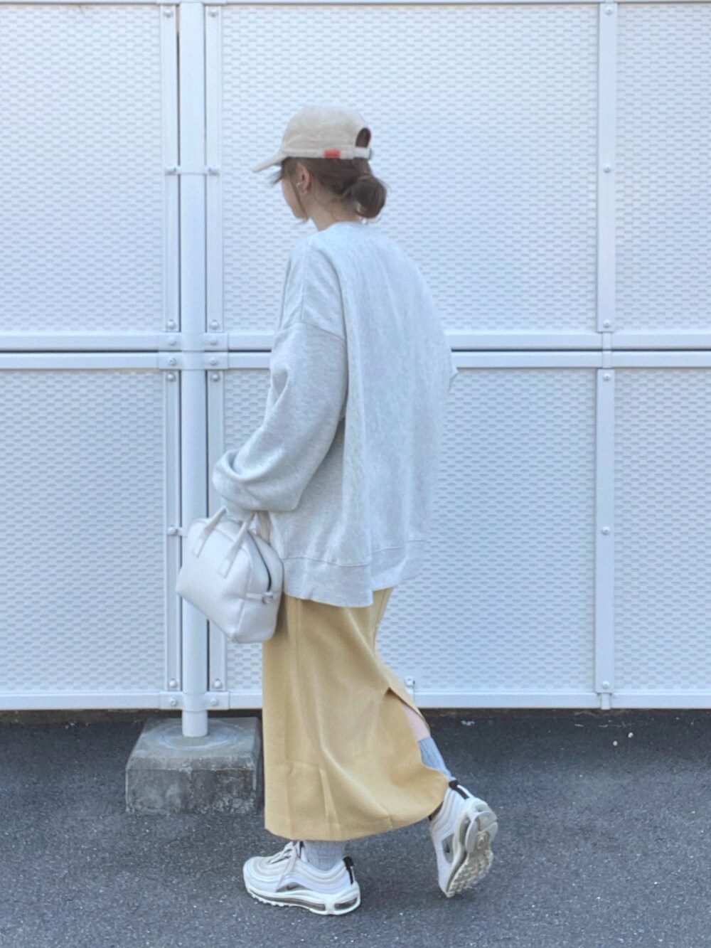 ベージュ系のスウェット、イエロー系のスカート、ホワイト系のボストンバッグを着用したレディースの冬コーディネートの2枚目の写真