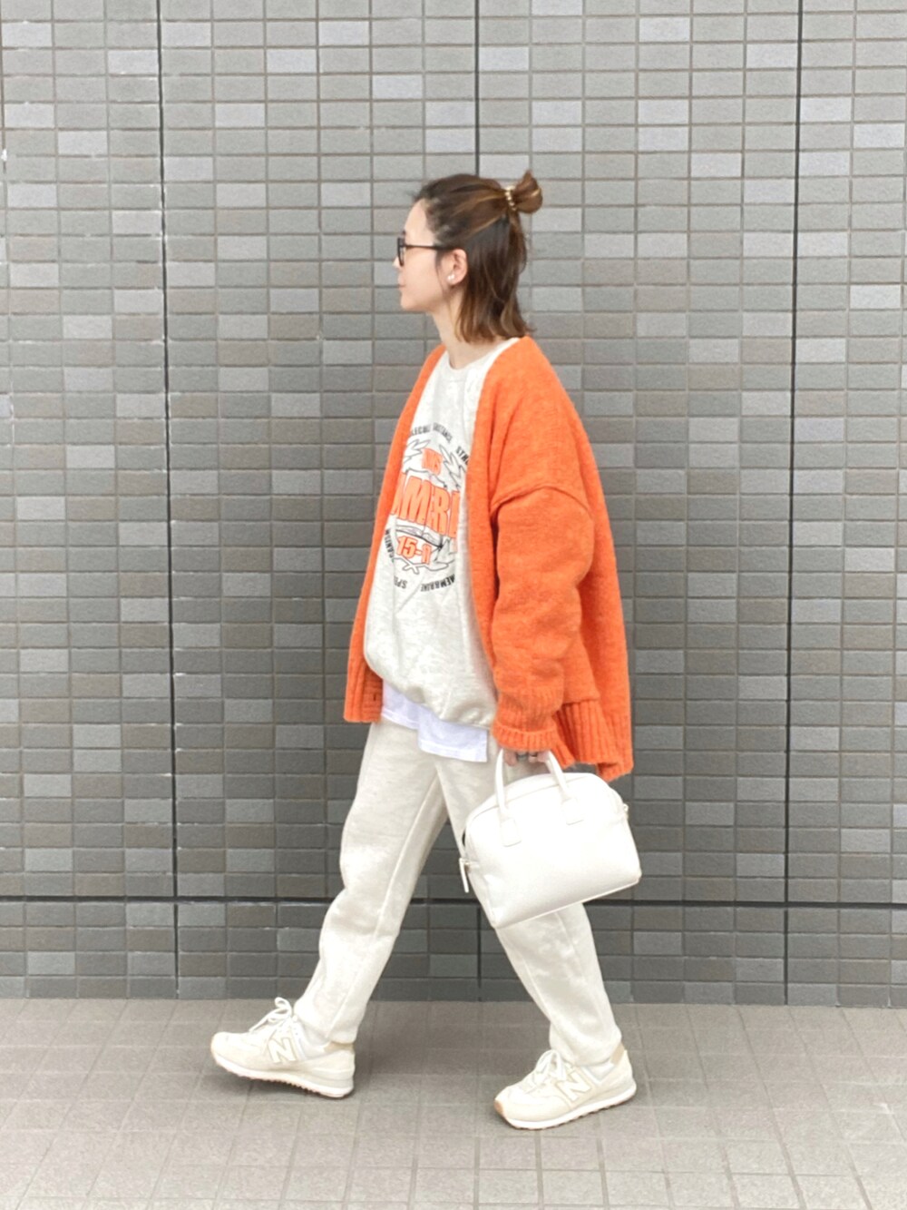 オレンジ系のカーディガン/ボレロ、ホワイト系のスウェット、ホワイト系のボストンバッグを着用したレディースの秋コーディネートの2枚目の写真