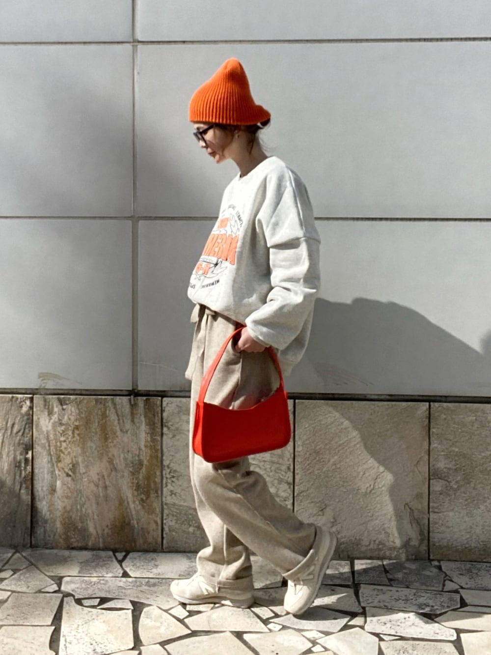 ベージュ系のパンツ、ホワイト系のスウェット、オレンジ系のショルダーバッグを着用したレディースの冬コーディネートの2枚目の写真