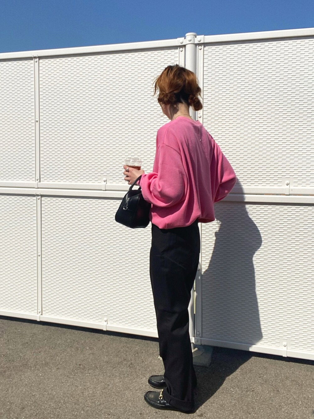 ブラック系のスラックス、ピンク系のTシャツ/カットソー、ブラック系のボストンバッグを着用したレディースの春コーディネートの3枚目の写真