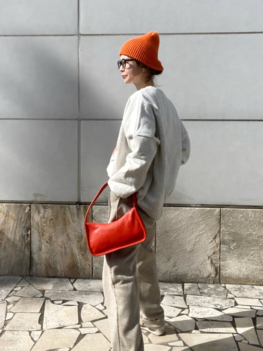 ベージュ系のパンツ、ホワイト系のスウェット、オレンジ系のショルダーバッグを着用したレディースの冬コーディネートの4枚目の写真