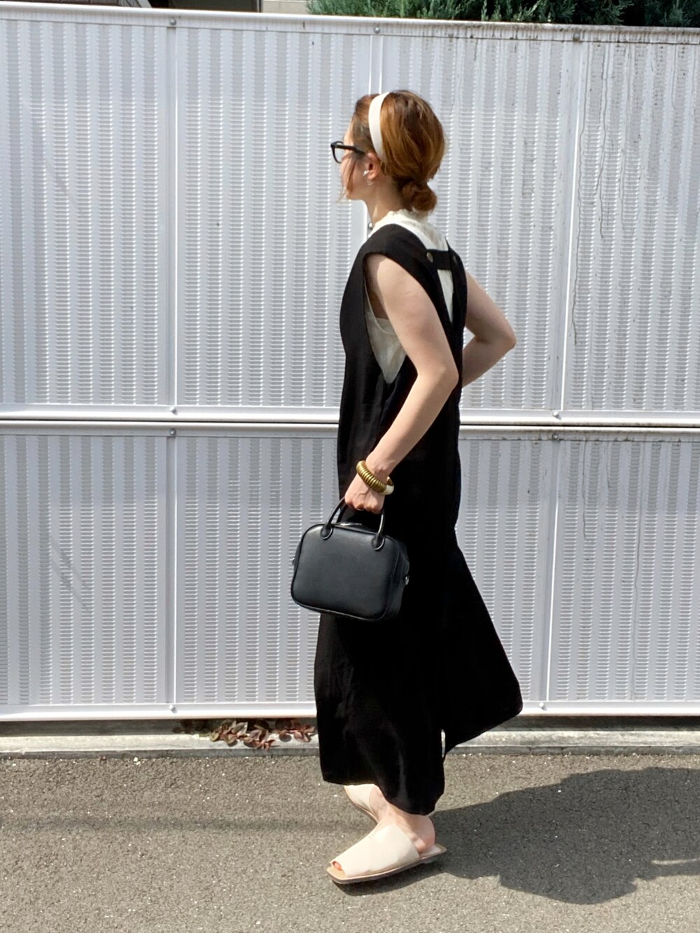 ブラック系のワンピース、ホワイト系のサンダル、ブラック系のボストンバッグを着用したレディースの夏コーディネートの4枚目の写真