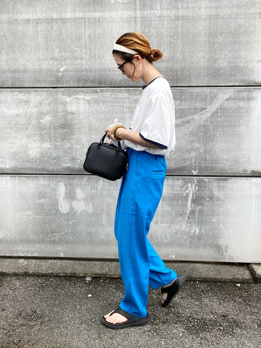 ブルー系のスラックス、ホワイト系のTシャツ/カットソー、ブラック系のボストンバッグを着用したレディースの夏コーディネートの2枚目の写真