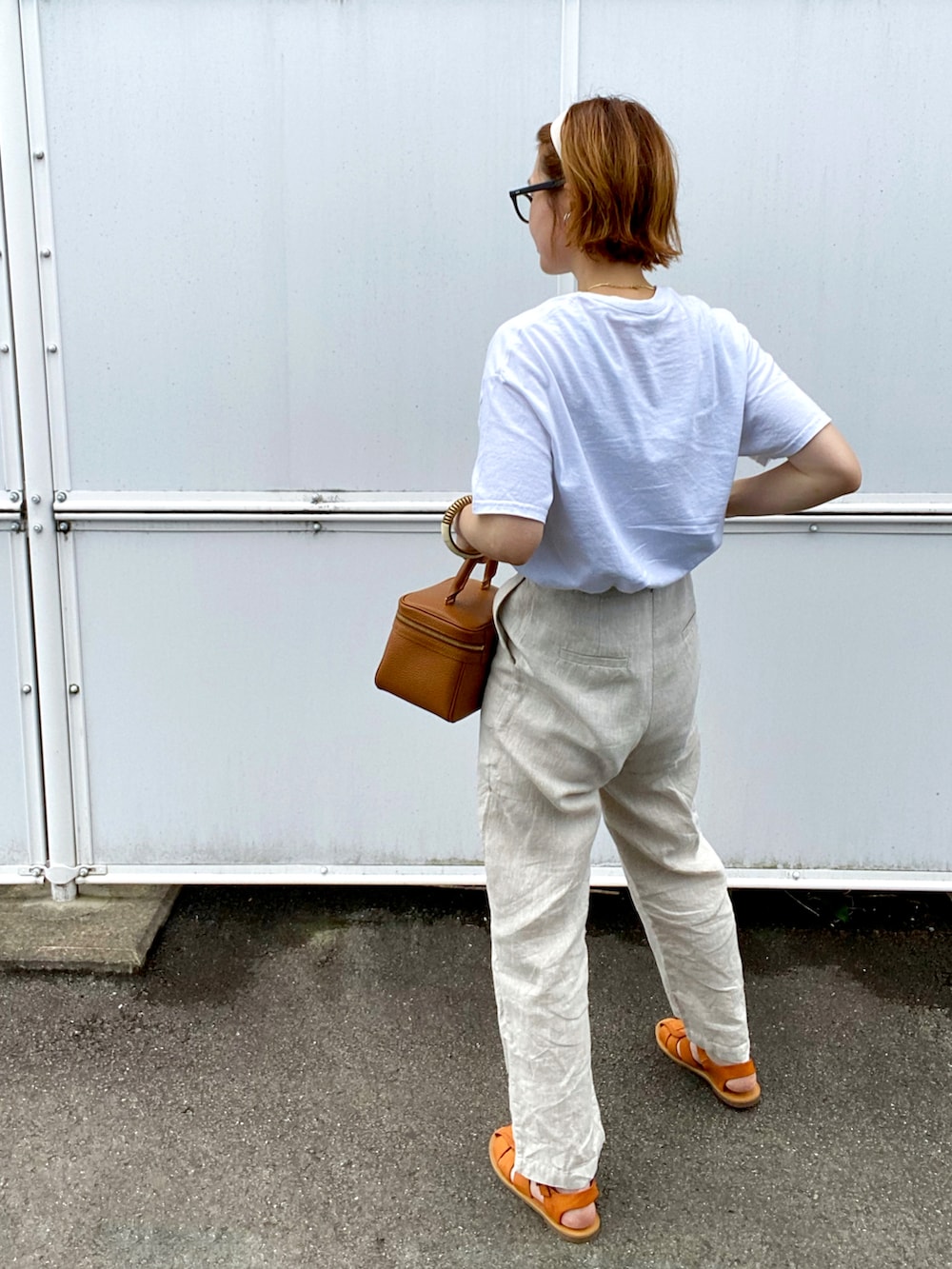 ホワイト系のTシャツ/カットソー、ベージュ系のスラックス、ブラウン系のサンダルを着用したレディースの夏コーディネートの2枚目の写真