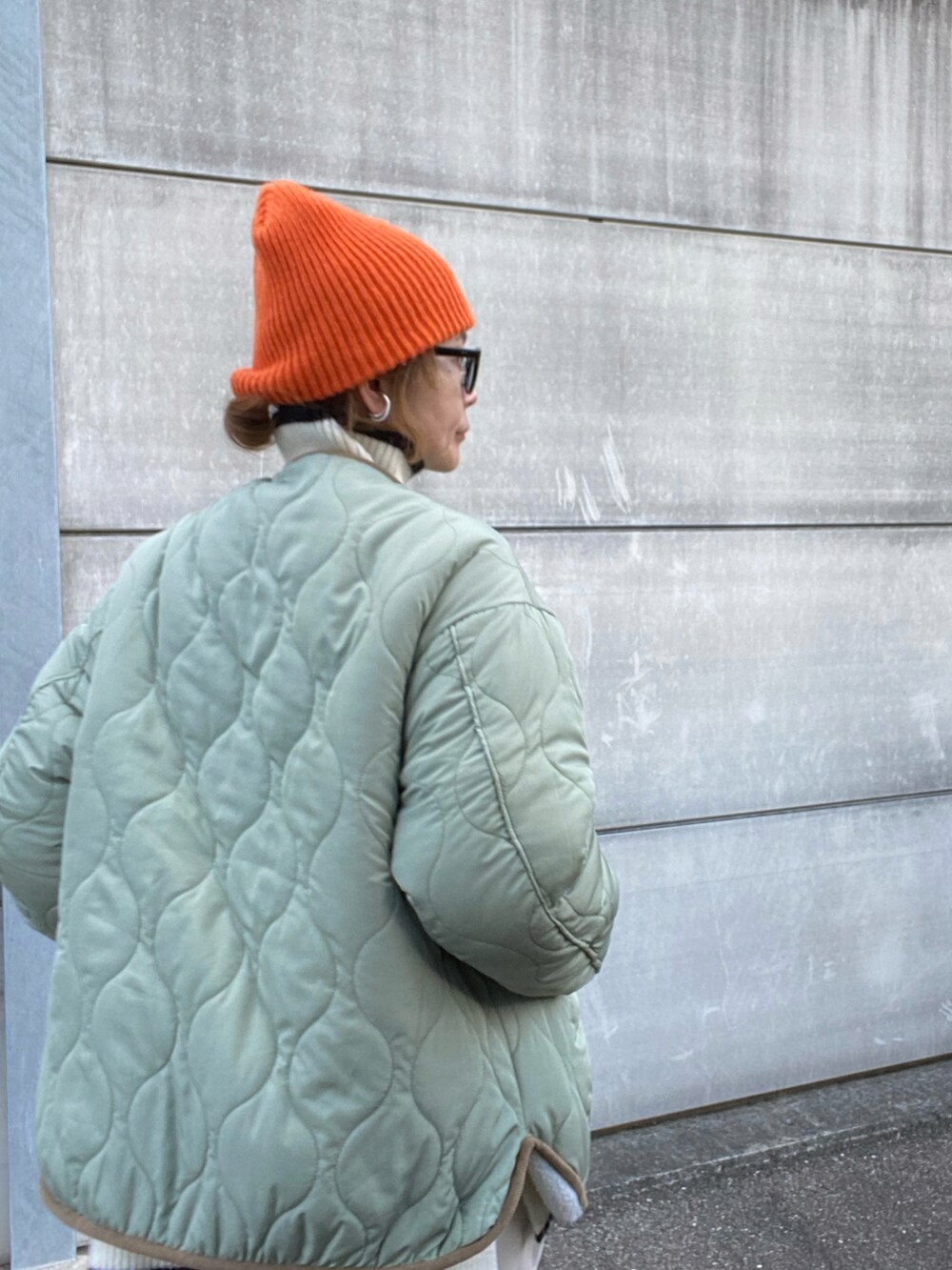 ホワイト系のノーカラージャケット、ホワイト系のニット/セーター、ホワイト系のスニーカーを着用したレディースの冬コーディネートの3枚目の写真