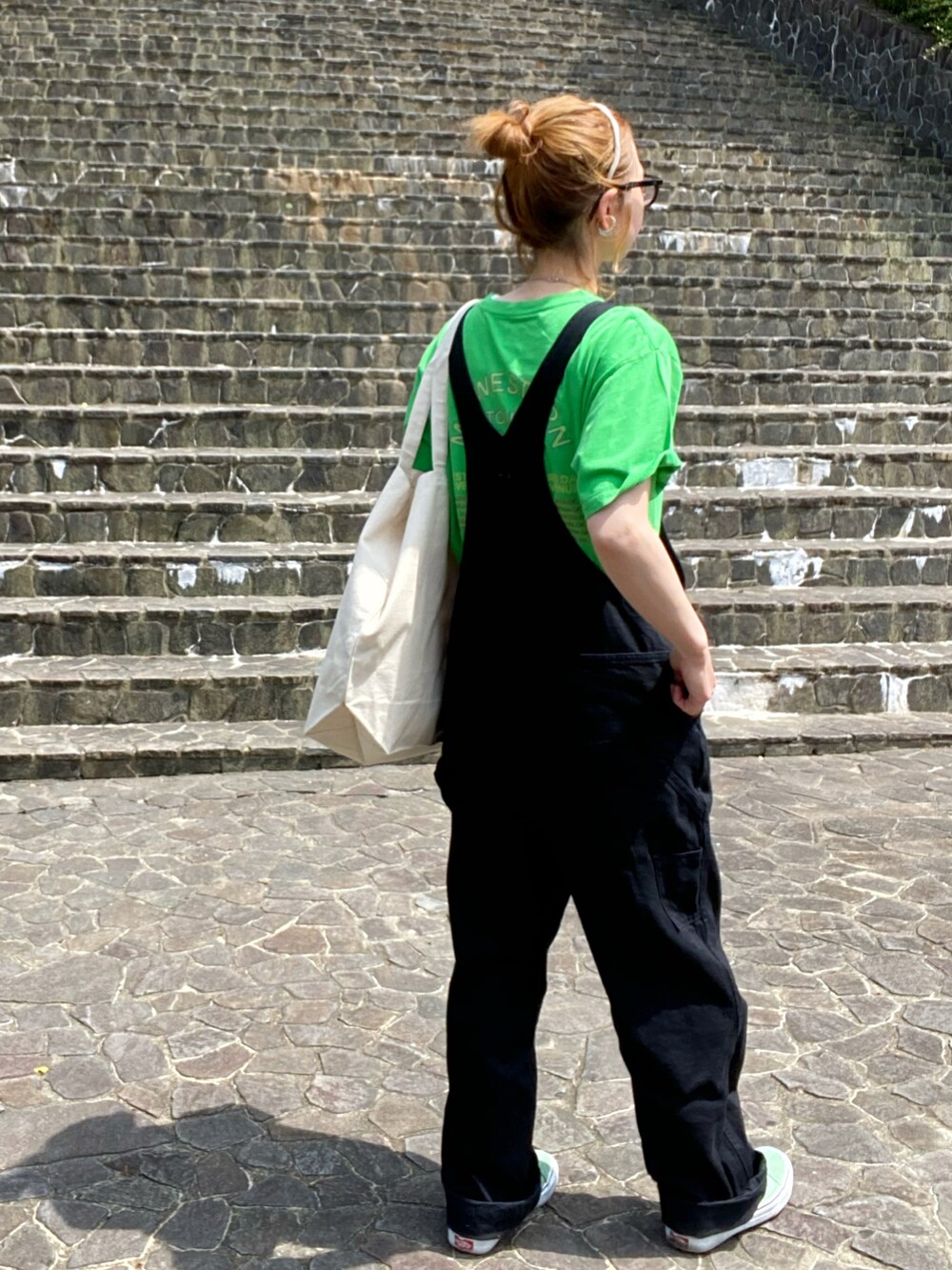 ブラック系のサロペット/オーバーオール、グリーン系のTシャツ/カットソー、グリーン系のスニーカーを着用したレディースの春コーディネートの3枚目の写真