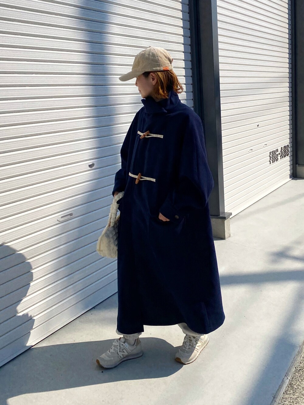 ブルー系のダッフルコート、ホワイト系のスニーカー、ホワイト系のキャップを着用したレディースの秋コーディネートの2枚目の写真