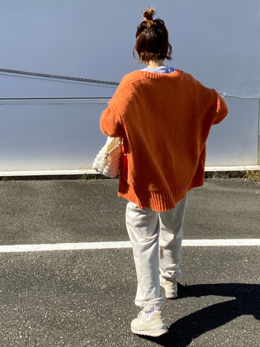 グレー系のスウェット、オレンジ系のカーディガン/ボレロ、ホワイト系のスニーカーを着用したレディースの秋コーディネートの3枚目の写真