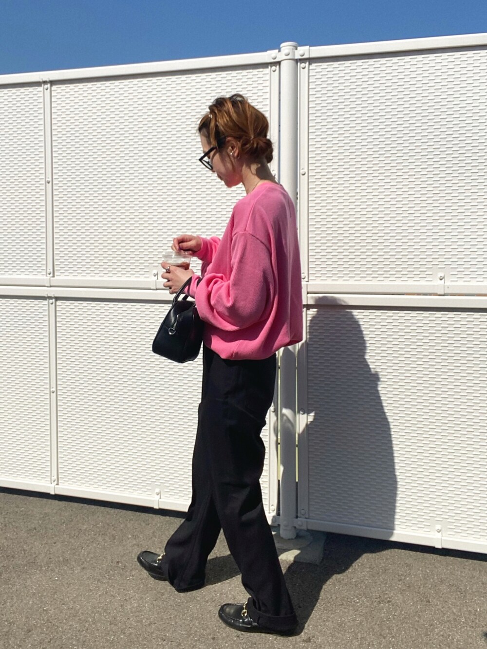 ブラック系のスラックス、ピンク系のTシャツ/カットソー、ブラック系のボストンバッグを着用したレディースの春コーディネートの4枚目の写真