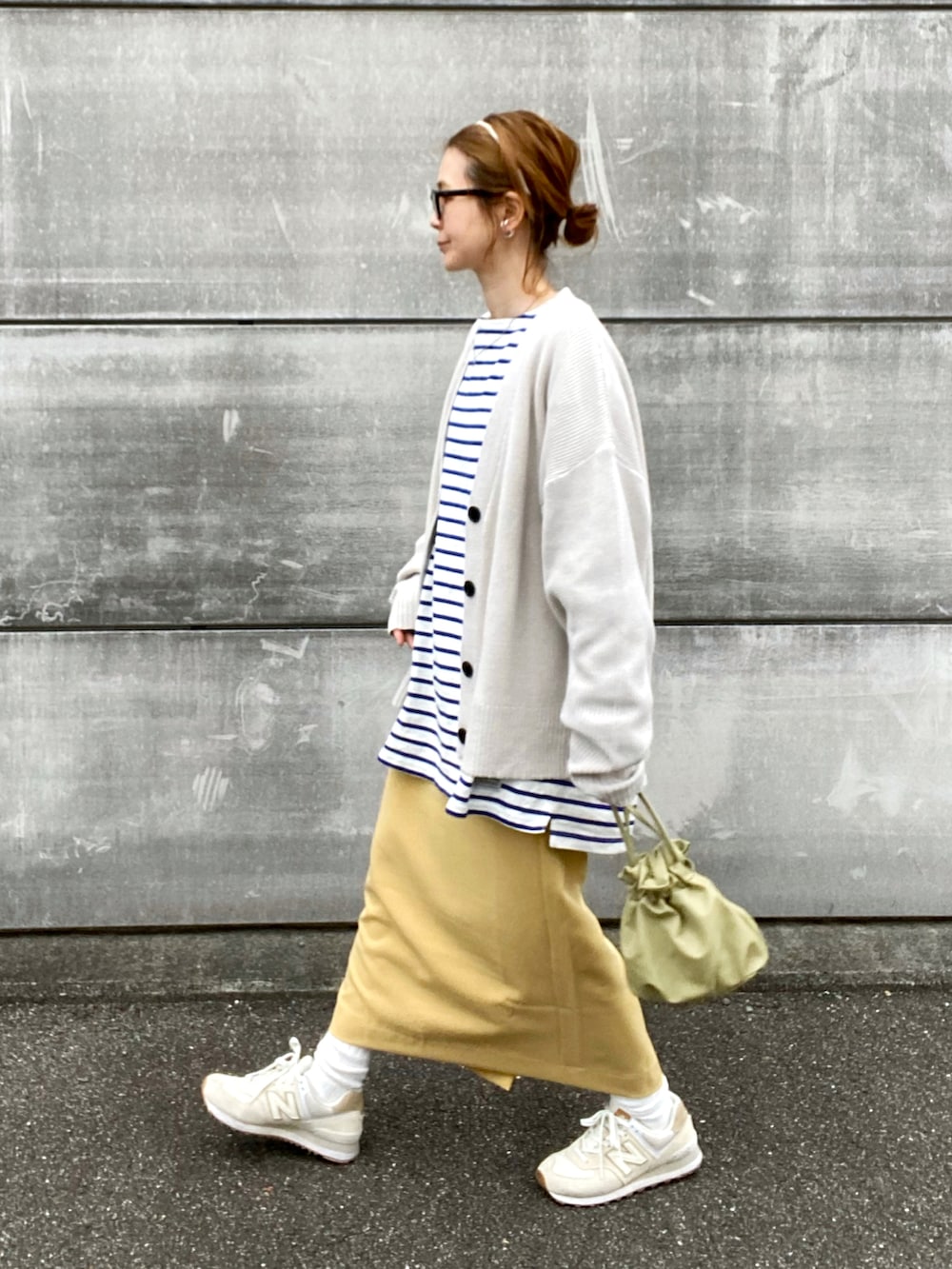 イエロー系のスカート、ホワイト系のカーディガン/ボレロ、ホワイト系のスニーカーを着用したレディースの春コーディネートの4枚目の写真