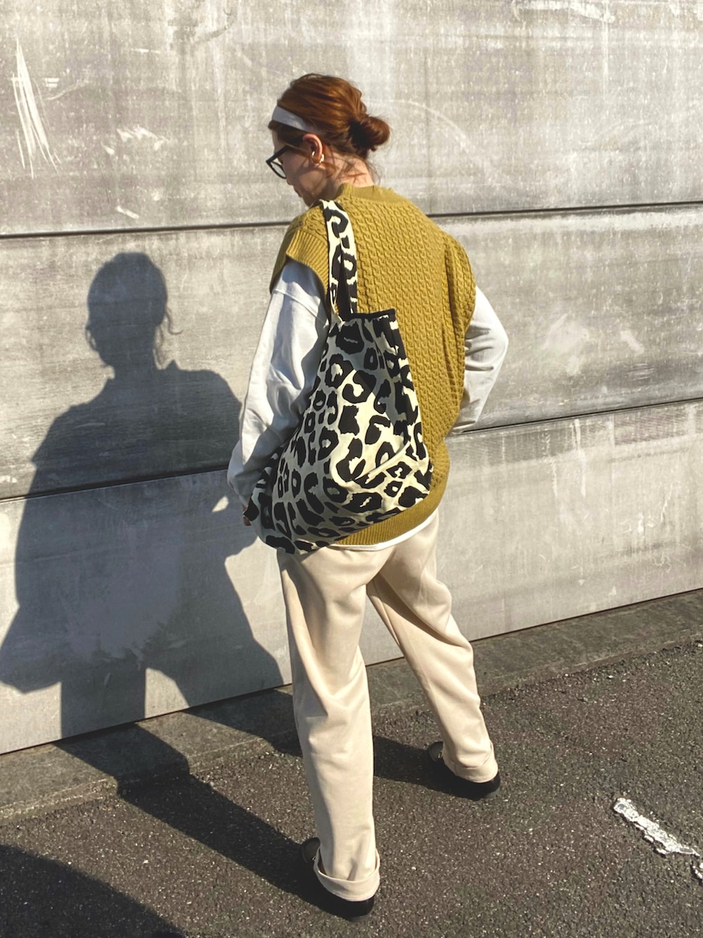 イエロー系のベスト、ホワイト系のTシャツ/カットソー、ブラック系のトートバッグを着用したレディースの春コーディネートの3枚目の写真