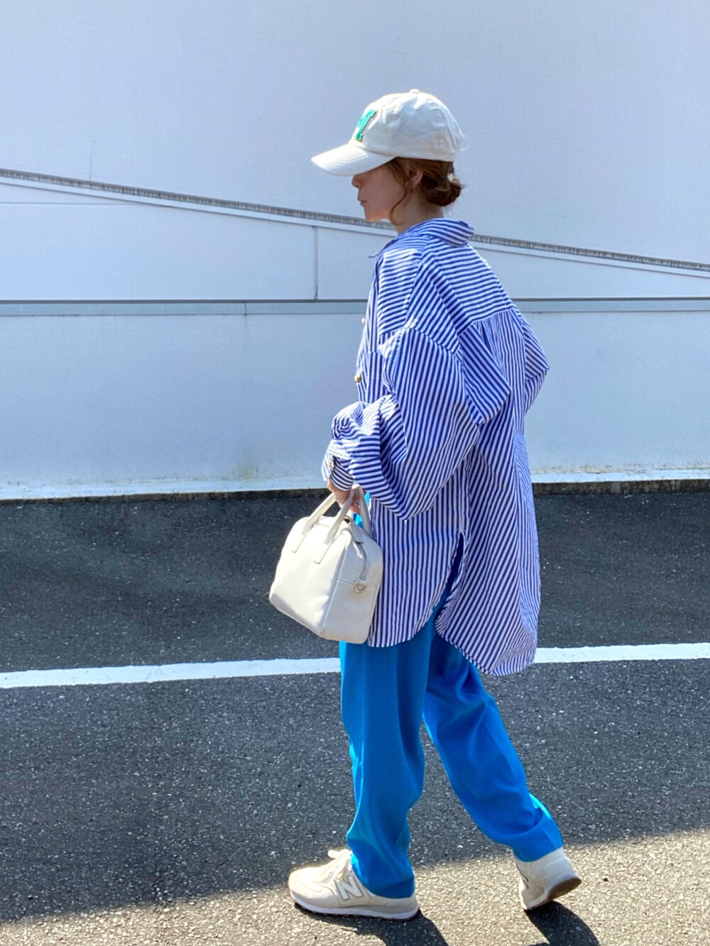 ブルー系のシャツ/ブラウス、ブルー系のスラックス、ホワイト系のボストンバッグを着用したレディースの春コーディネートの2枚目の写真