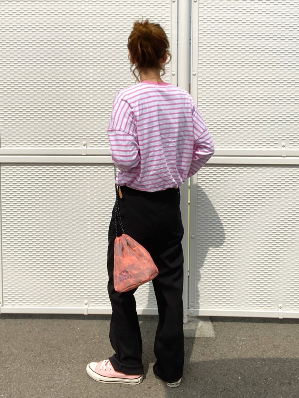 ブラック系のスラックス、ピンク系のスニーカー、オレンジ系のショルダーバッグを着用したレディースの春コーディネートの2枚目の写真