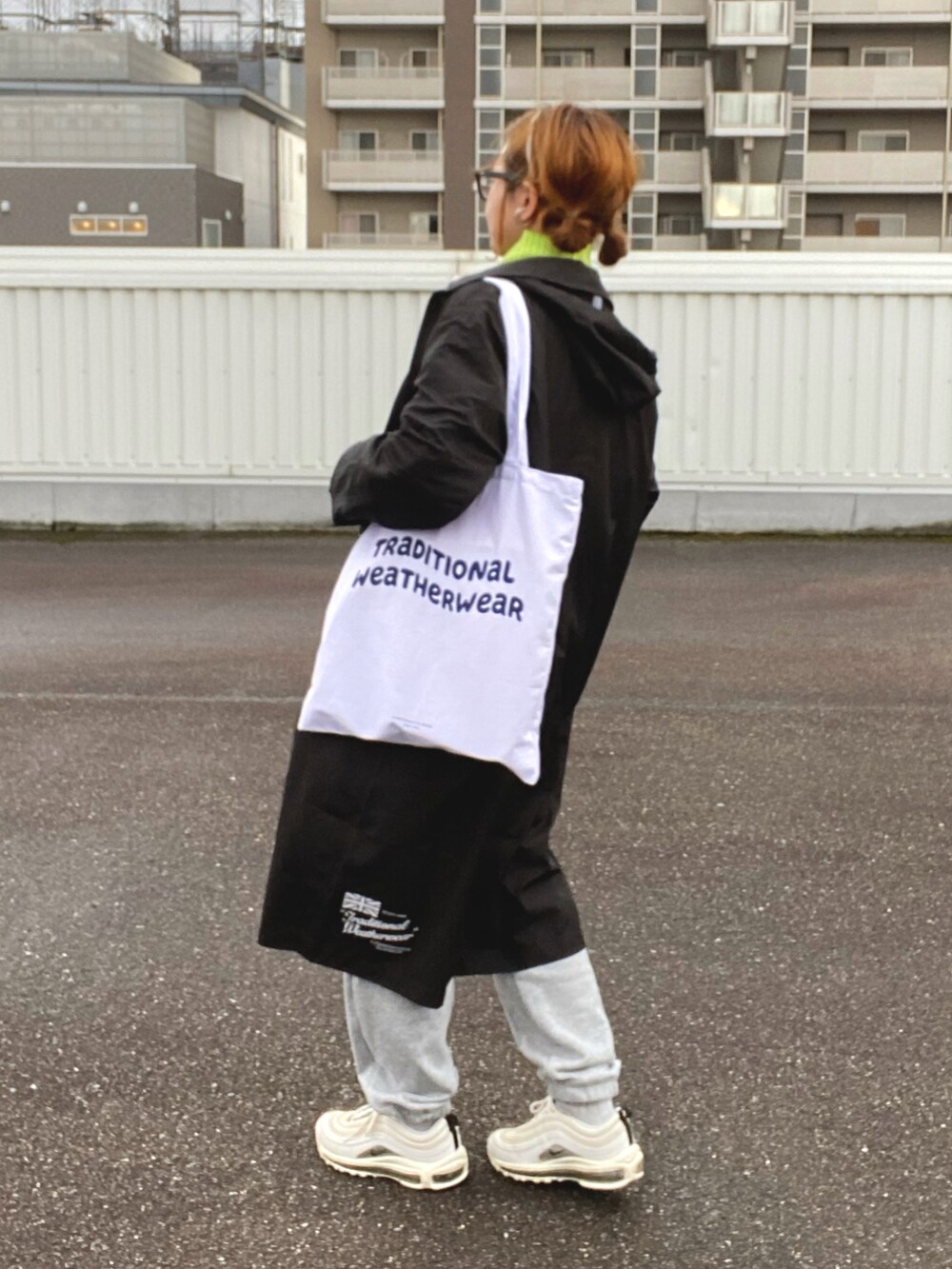 ホワイト系のトートバッグ、ブラック系のカーディガン/ボレロ、グリーン系のニット/セーターを着用したレディースの春コーディネートの3枚目の写真