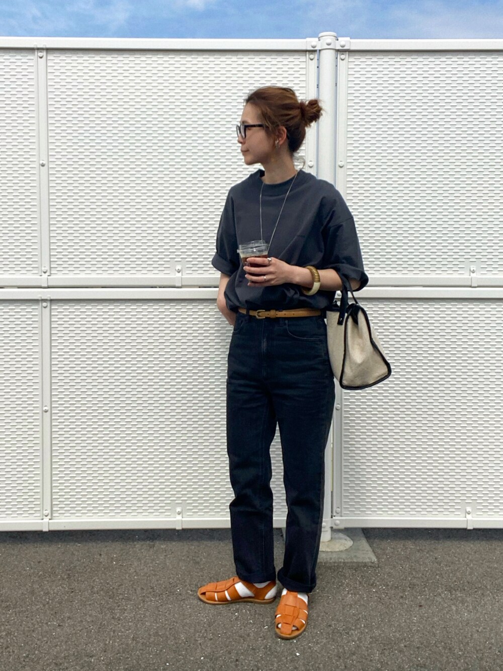 ブラウン系のサンダル、ブラック系のTシャツ/カットソー、ベージュ系のトートバッグを着用したレディースの春コーディネートの3枚目の写真