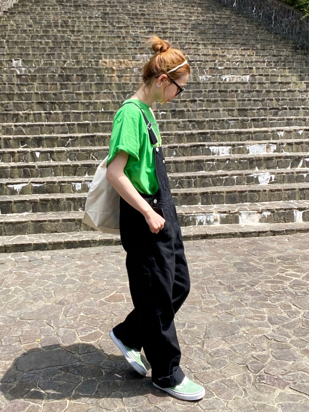 ブラック系のサロペット/オーバーオール、グリーン系のTシャツ/カットソー、グリーン系のスニーカーを着用したレディースの春コーディネートの2枚目の写真