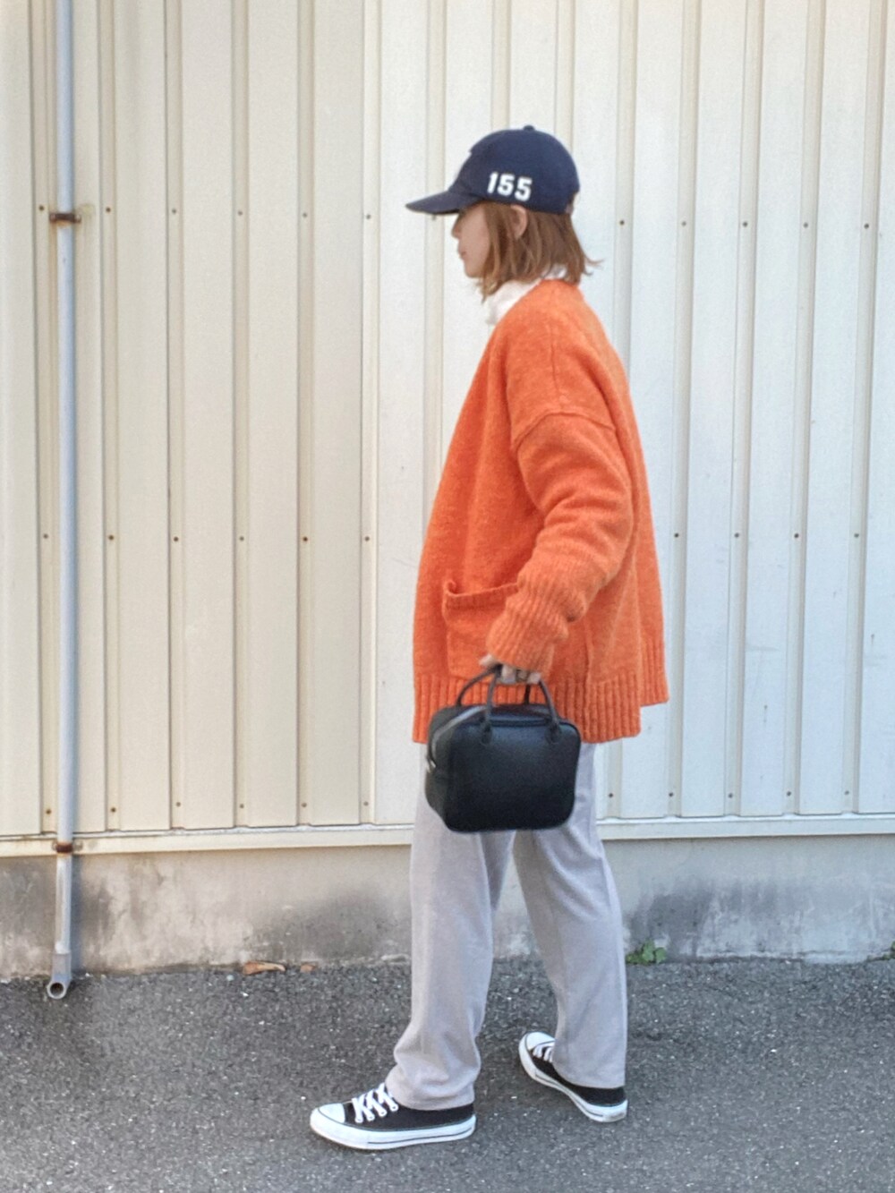 オレンジ系のカーディガン/ボレロ、ブラック系のボストンバッグ、グレー系のスラックスを着用したレディースの冬コーディネートの3枚目の写真