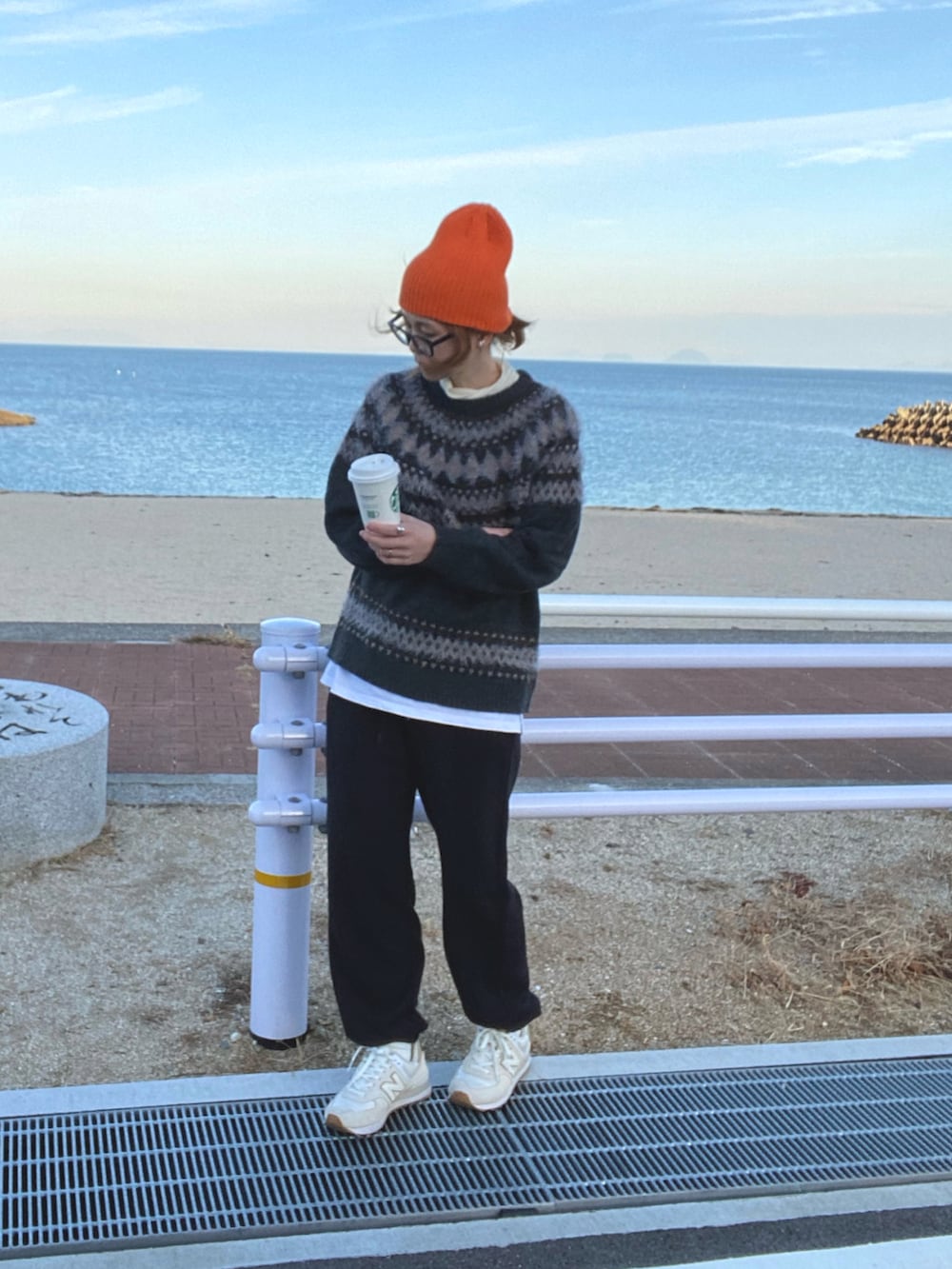 ブラック系のニット/セーター、ホワイト系のスニーカー、オレンジ系のニットキャップ/ビーニーを着用したレディースの冬コーディネートの3枚目の写真