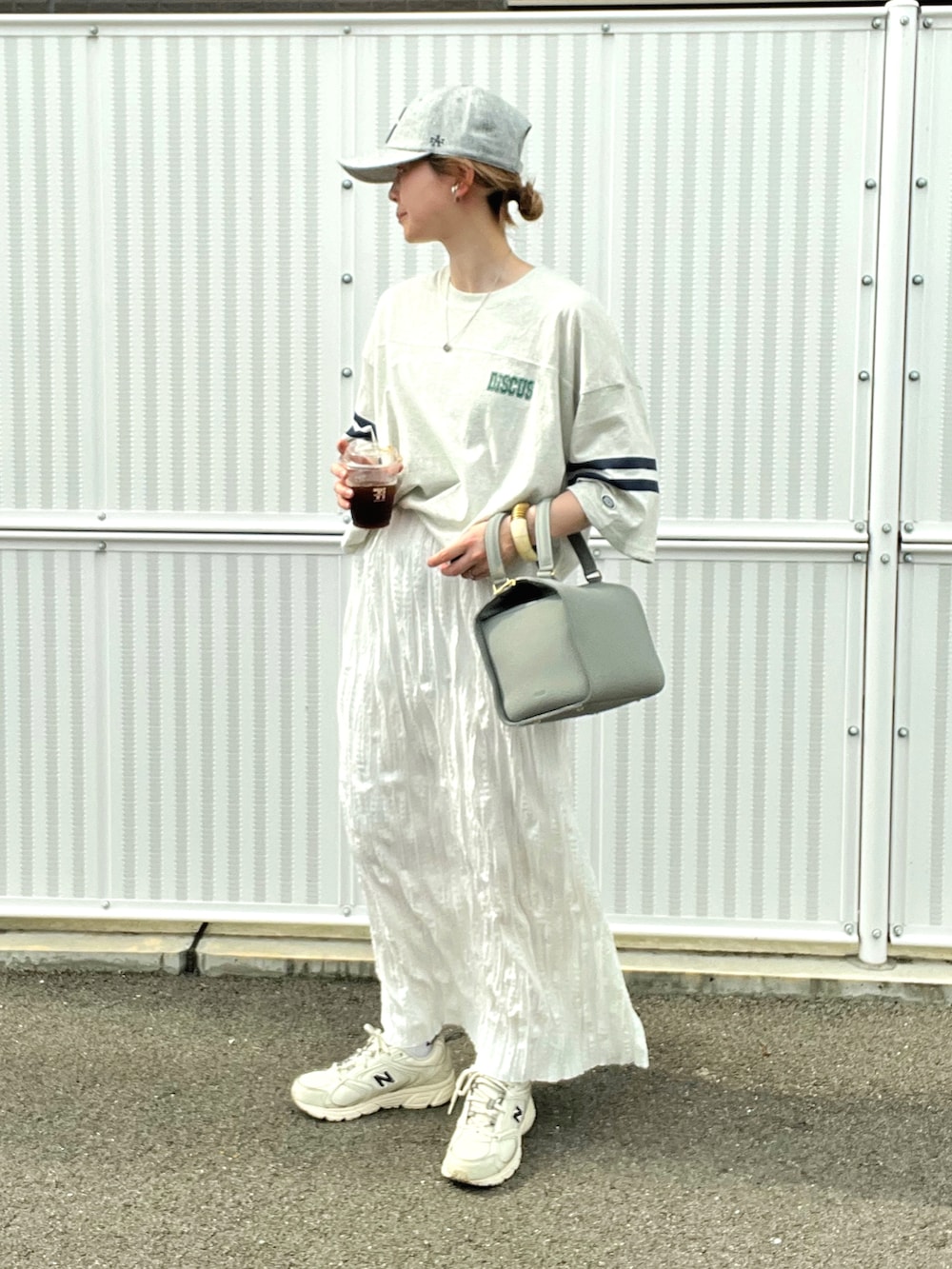 ベージュ系のTシャツ/カットソー、ホワイト系のスカート、ホワイト系のスニーカーを着用したレディースの夏コーディネートの2枚目の写真