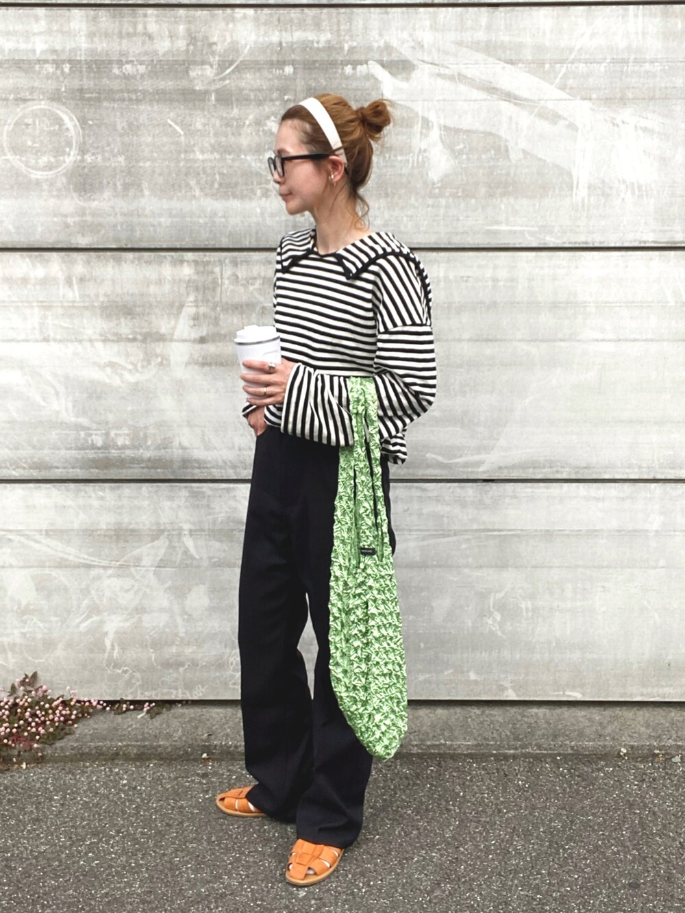 ブラック系のスラックス、ブラウン系のサンダル、ブルー系のトートバッグを着用したレディースの春コーディネートの2枚目の写真