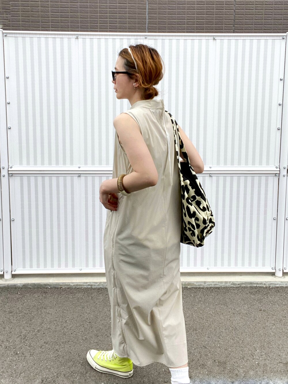 ベージュ系のワンピース、イエロー系のスニーカー、ブラック系のトートバッグを着用したレディースの春コーディネートの2枚目の写真