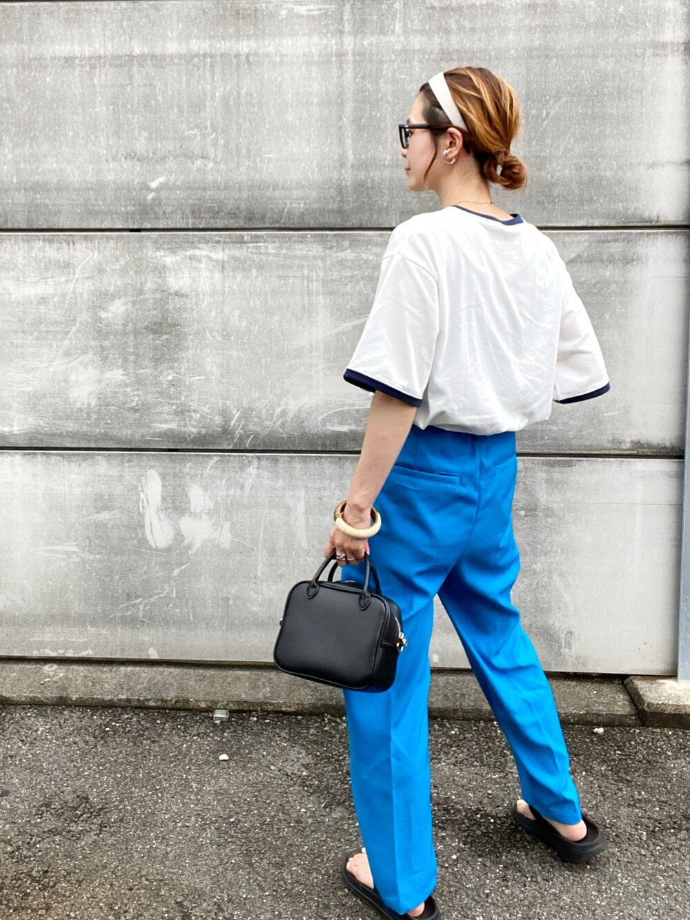 ブルー系のスラックス、ホワイト系のTシャツ/カットソー、ブラック系のボストンバッグを着用したレディースの夏コーディネートの3枚目の写真