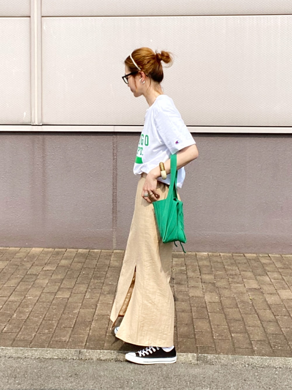 ベージュ系のスカート、ブラック系のスニーカー、グリーン系のトートバッグを着用したレディースの春コーディネートの2枚目の写真