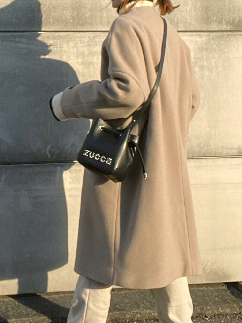 ブラック系のショルダーバッグ、ブラウン系のその他アウター、ホワイト系のニット/セーターを着用したレディースの冬コーディネートの3枚目の写真