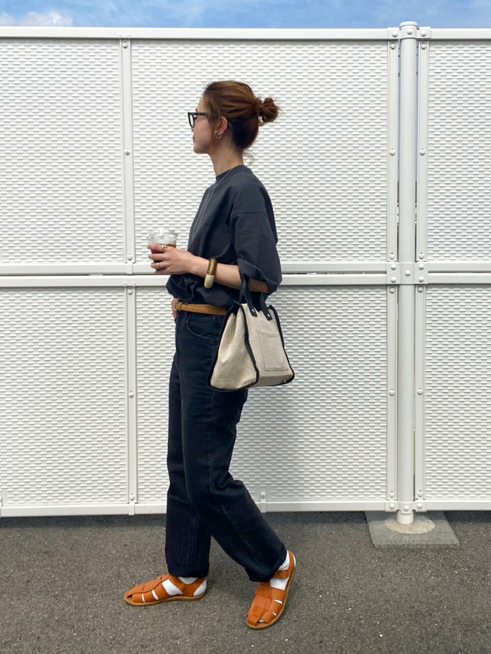 ブラウン系のサンダル、ブラック系のTシャツ/カットソー、ベージュ系のトートバッグを着用したレディースの春コーディネートの2枚目の写真