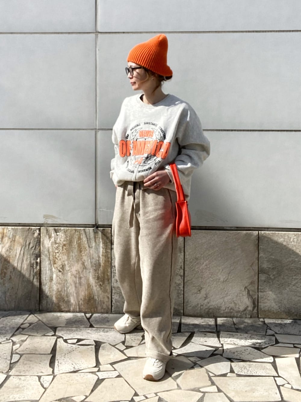 ベージュ系のパンツ、ホワイト系のスウェット、オレンジ系のショルダーバッグを着用したレディースの冬コーディネートの3枚目の写真