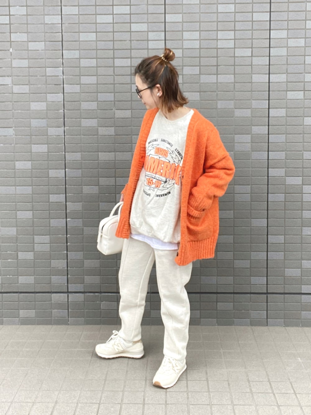 オレンジ系のカーディガン/ボレロ、ホワイト系のスウェット、ホワイト系のボストンバッグを着用したレディースの秋コーディネートの3枚目の写真